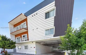 Contemporary multi-story exterior featuring a mix of horizontal white siding, dark vertical panels, and wood-finish accents