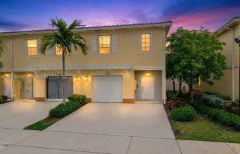 Two-story exterior featuring a tile roof, stucco finish, white-framed windows, a covered pergola accent, and an attached single-car garage with a concrete driveway