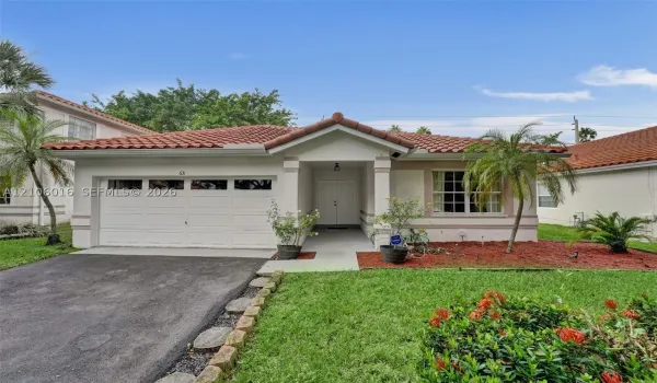 Stucco exterior featuring a tiled roof, covered entryway, multi-panel garage door, and defined landscape beds