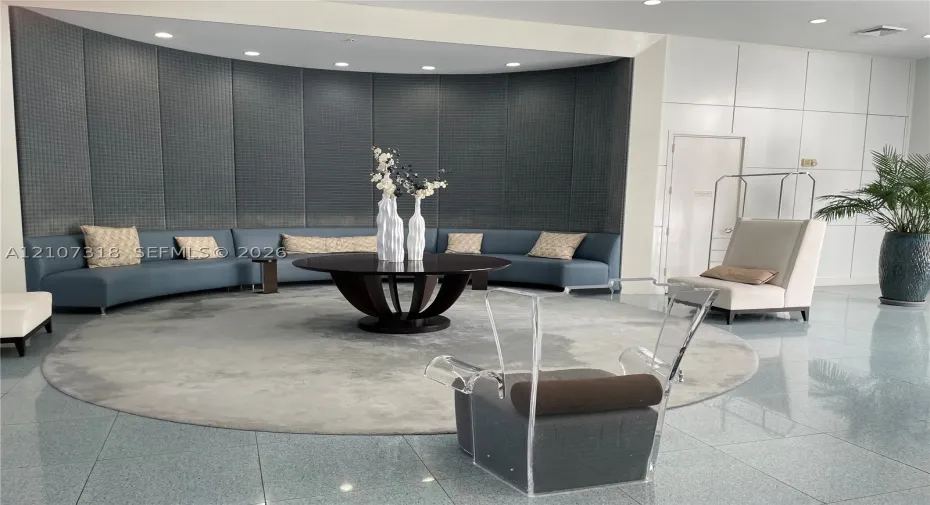 Curved wall with charcoal-toned grid-patterned paneling, polished stone flooring, and recessed ceiling lighting