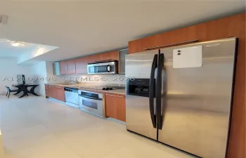 Kitchen featuring flat-panel wood-finish cabinetry, stainless steel appliances, stone-surface countertops, and tile flooring