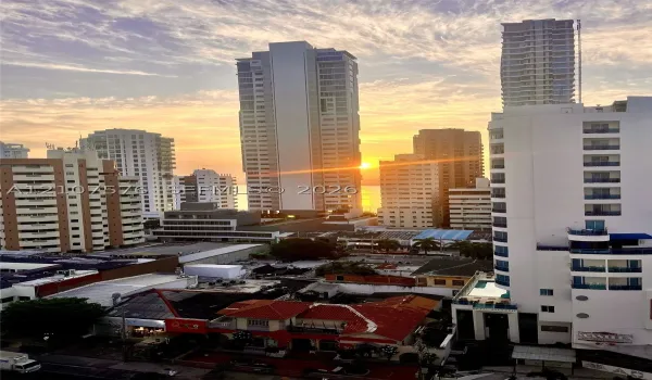 High-rise urban panorama featuring a densely developed cityscape, multi-story residential towers, and a sunset horizon
