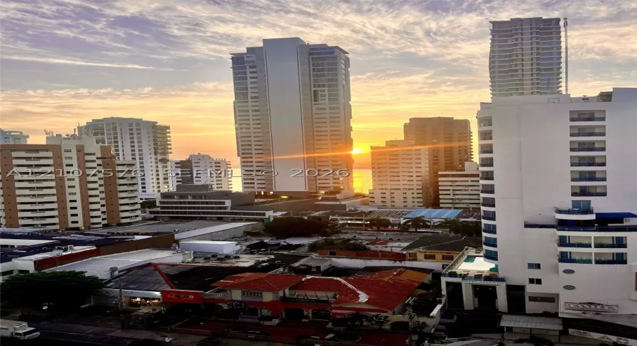 High-rise urban panorama featuring a densely developed cityscape, multi-story residential towers, and a sunset horizon