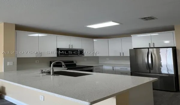 Kitchen featuring white flat-panel cabinetry, quartz countertops, a stainless steel undermount sink with a gooseneck faucet, and stainless steel appliances