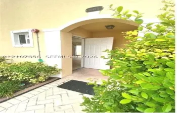 Covered entryway featuring a stucco archway, herringbone-patterned paved walkway, and built-in exterior lighting