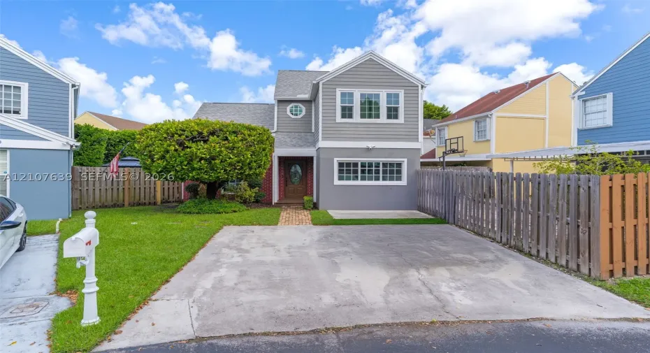 Multi-story residence with horizontal siding, brick masonry, asphalt shingle roofing, paved driveway, and manicured lawn