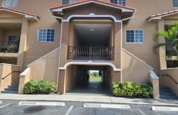 Stucco exterior with an arched entryway, elevated balcony featuring metal railings, and two sets of concrete exterior stairs