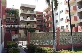 Multi-story residential complex featuring private balconies, a central courtyard, a screened swimming pool, and decorative concrete masonry privacy wall