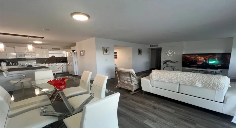 Open-concept layout featuring wood-finish flooring, white cabinetry, a breakfast bar, and recessed lighting