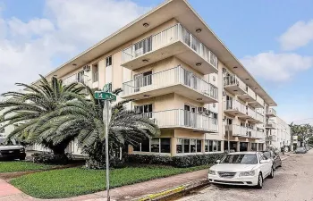 Multi-story building exterior featuring a stucco facade, private balconies with metal railings, and integrated surface-mounted lighting