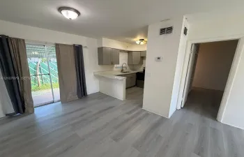 Kitchen area featuring wood-finish flooring, a breakfast bar with solid-surface countertops, grey cabinetry, and a sliding glass door