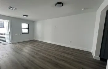Interior space featuring wood-finish flooring, white walls, dual flush-mount ceiling light fixtures, and a single-pane window