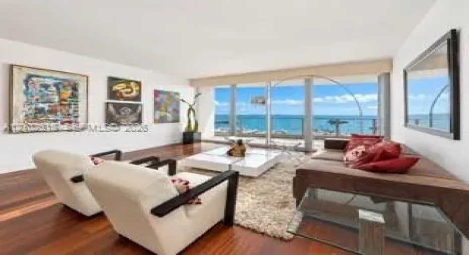 Living area featuring floor-to-ceiling glass sliding doors, wood-finish flooring, and a glass-paneled balcony