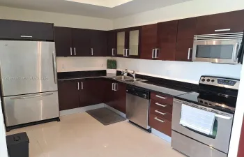 Kitchen featuring dark wood-finish cabinetry, solid surface countertops, stainless steel appliances, double-basin sink with arched faucet, and tile flooring