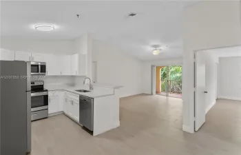 Modern kitchen featuring white cabinetry, stainless steel appliances, a breakfast bar, and wood-finish flooring