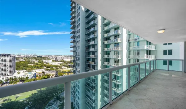 Covered balcony featuring stone-finish flooring, glass panel railings, and an integrated ceiling light fixture