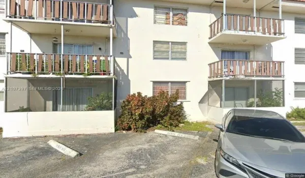 Multi-story stucco exterior featuring screened balconies, open-air upper-level balconies, and designated surface parking spaces