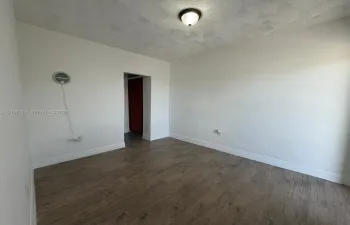 Neutral-toned walls, textured ceiling, wood-finish flooring, and semi-flush mount ceiling fixture