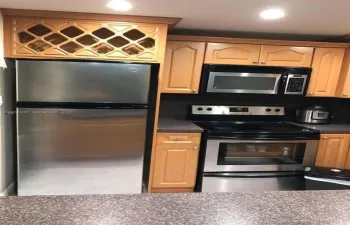 Kitchen featuring wood cabinetry, stainless steel appliances, built-in wine rack, and stone-finish countertops