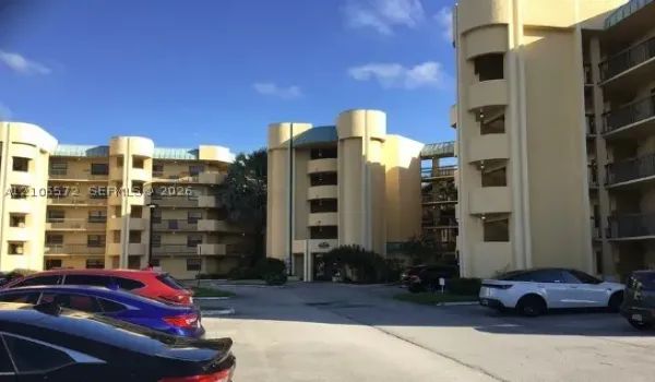 Multi-story building exterior featuring curved architectural towers, metal roofing elements, and private balconies with railings