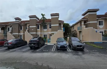 Multi-level exterior featuring stucco siding, tiled roofing, concrete stairs, and paved surface parking
