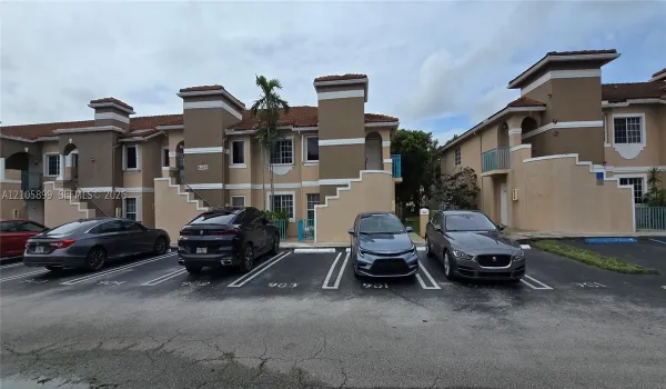 Multi-level exterior featuring stucco siding, tiled roofing, concrete stairs, and paved surface parking