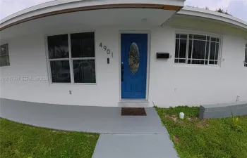 Exterior entry featuring a painted front door with an oval glass insert, multi-pane windows, a covered front porch, and a concrete walkway