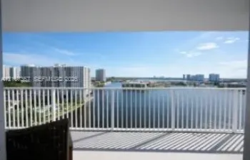 Private balcony featuring vertical white metal railings, concrete flooring, and water frontage