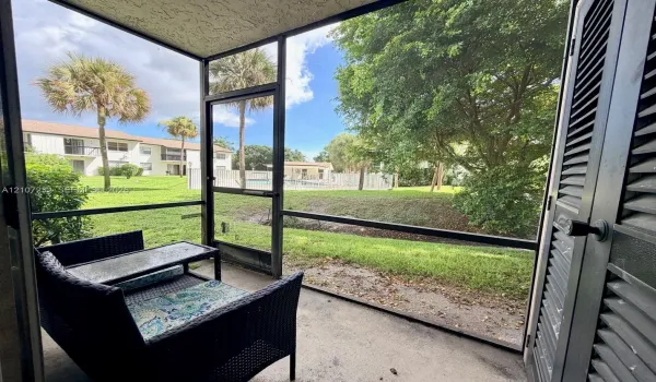 Screened-in patio with concrete flooring, louvered utility closet door, and metal frame enclosure