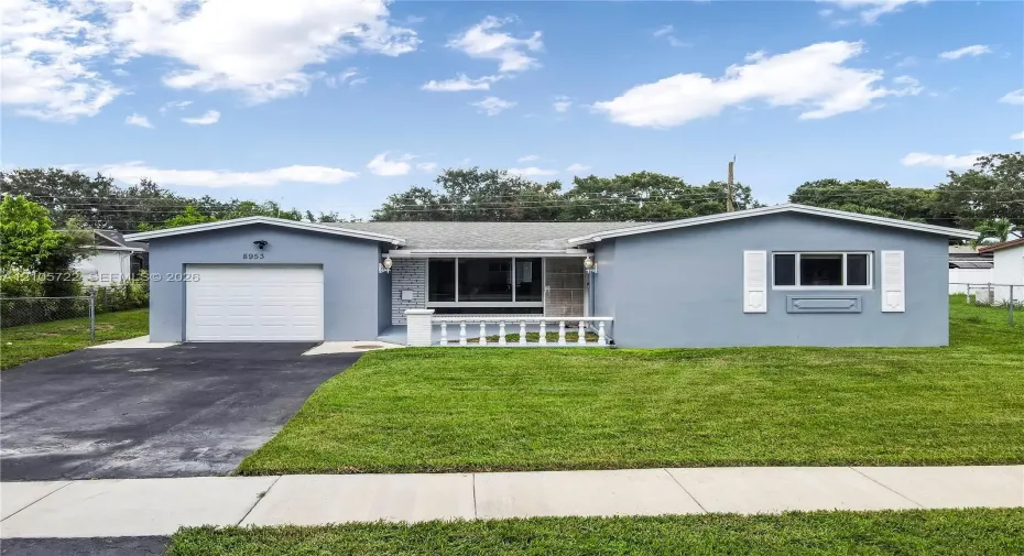 Single-story residence featuring a gray stucco exterior, white louvered shutters, an attached one-car garage, and a decorative white porch railing
