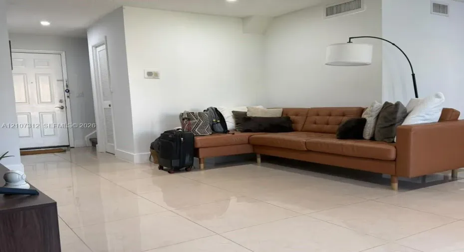 Large-format tile flooring, recessed ceiling lighting, and a six-panel entry door