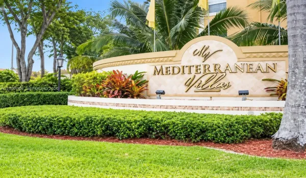 Community monument signage featuring dimensional gold-tone lettering, decorative stone masonry, integrated ground lighting, and professional perimeter landscaping with manicured shrubbery