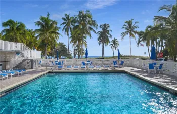 Rectangular swimming pool featuring tile coping, a multi-level paver deck, and decorative concrete balustrade perimeter fencing