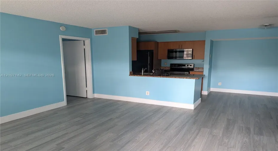 Kitchen featuring wood-finish cabinetry, stone-texture countertops, and integrated stainless steel microwave and oven