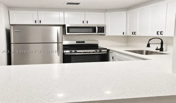 Kitchen featuring white shaker-style cabinetry, stainless steel appliances, quartz countertops, a white subway tile backsplash, and a matte black gooseneck faucet