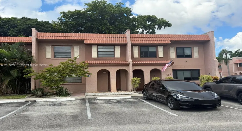 Two-story stucco exterior featuring arched entryway detailing, tiled roofline, and louvered shutters