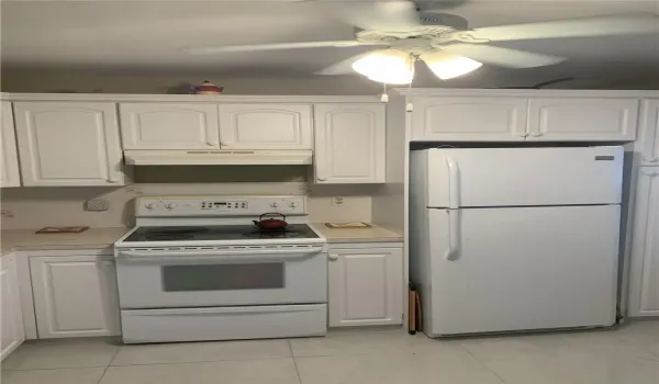 Kitchen featuring white cabinetry, solid-surface countertops, electric range, top-freezer refrigerator, and ceiling-mounted light fixture