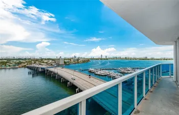 Covered balcony featuring concrete flooring and a blue-tinted glass railing