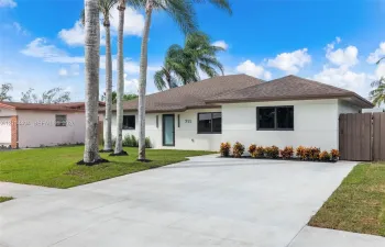 Single-story residence featuring a neutral stucco exterior, a concrete driveway, modern dark-framed windows, and a privacy fence