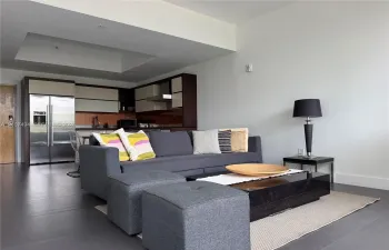 Open-concept area featuring oversized neutral floor tiling, recessed ceiling detail, and kitchen cabinetry with a two-tone finish