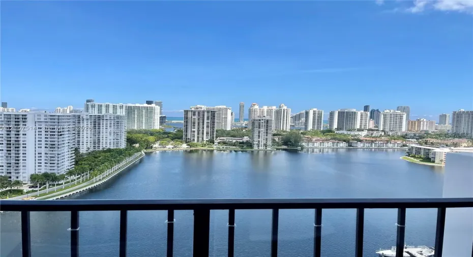 Black metal balcony railing overlooking a large lake and urban skyline