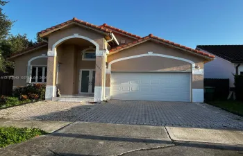 Stucco exterior featuring arched architectural detailing, tile roof, dual-glass panel entry door, and paver driveway