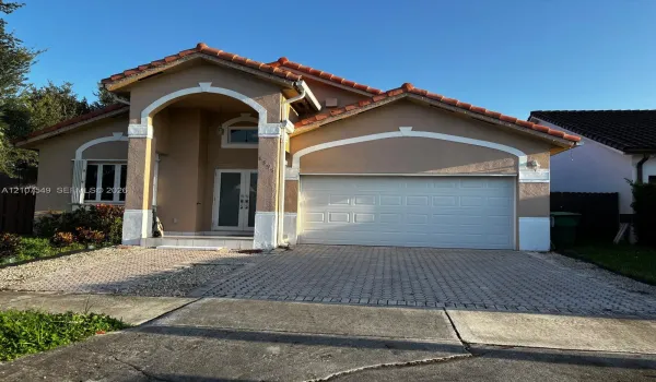 Stucco exterior featuring arched architectural detailing, tile roof, dual-glass panel entry door, and paver driveway
