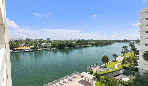 Waterfront terrace featuring stone paving, glass panel railings, and direct exposure to the waterway and city skyline