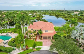 Two-story residence featuring a tile roof, three-car garage, private swimming pool, and water frontage on a landscaped lot