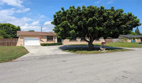 Single-story residence featuring a concrete driveway, attached one-car garage, mature landscaping, and wood-toned exterior finish