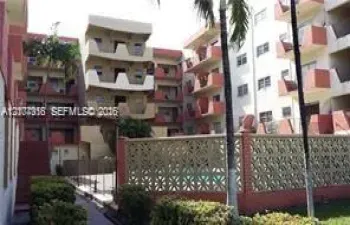 Multi-story residential complex featuring private balconies, a central courtyard, a screened swimming pool, and decorative concrete masonry privacy wall