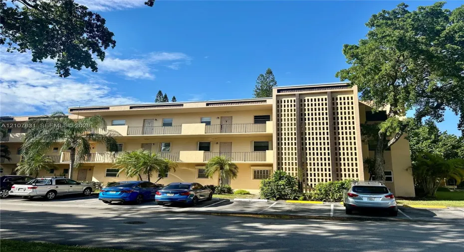 Multi-story exterior featuring stucco siding, decorative breeze block architectural detailing, and metal balcony railings