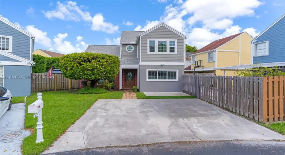 Multi-story residence with horizontal siding, brick masonry, asphalt shingle roofing, paved driveway, and manicured lawn