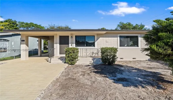 Single-story residence featuring a paved carport, stucco exterior, decorative metal porch railing, and dual-pane windows